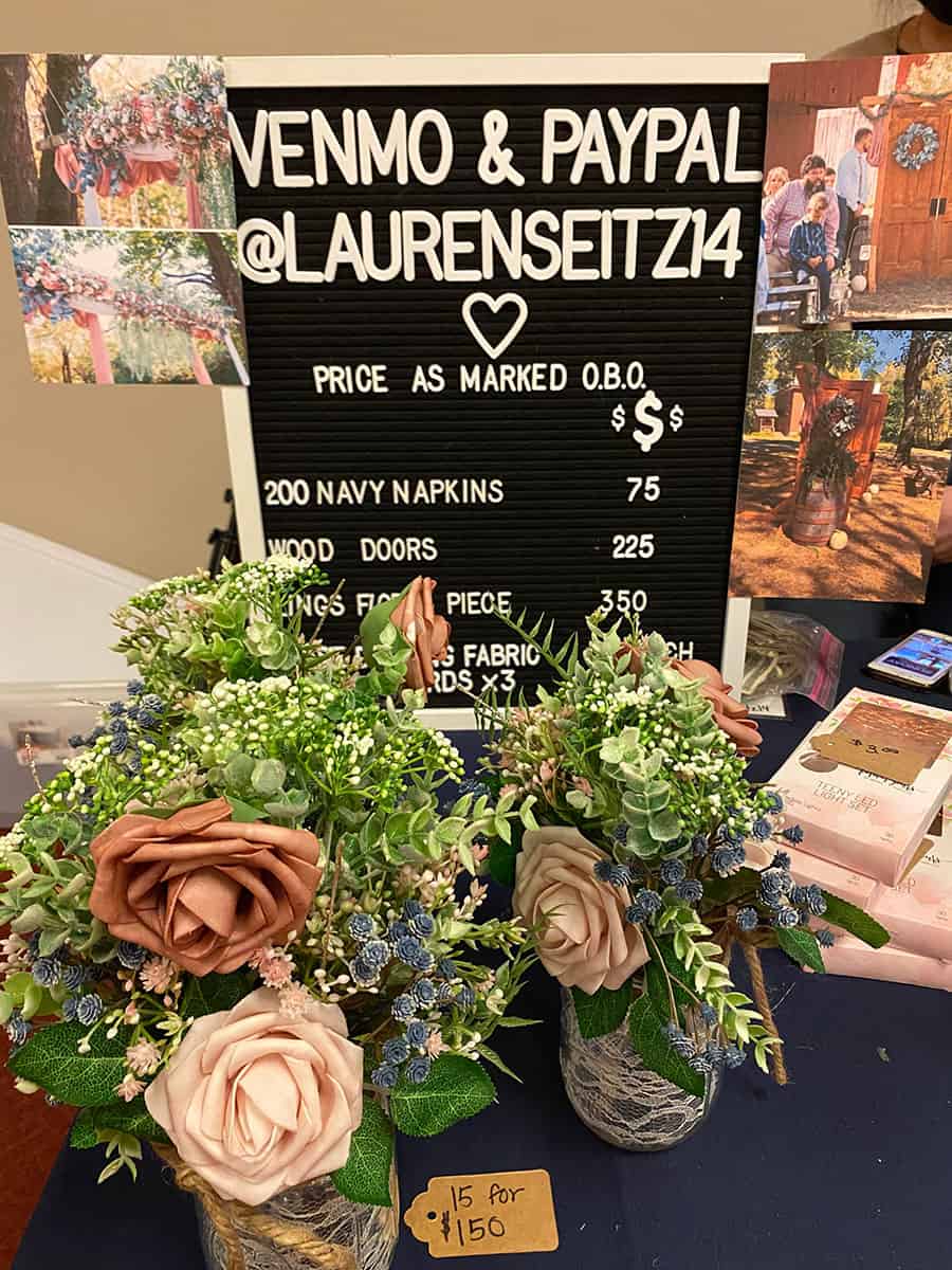 Two floral arrangements in jars on a table with a \$15 for \$150 sign, item price board, and Venmo/PayPal info for @LAURENSEITZ14.