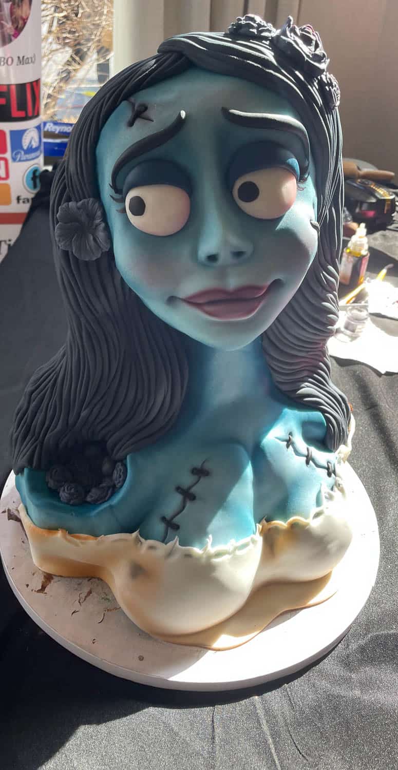 A cake shaped and decorated to look like a blue-skinned cartoon female character with long black hair and large eyes, positioned on a round base.