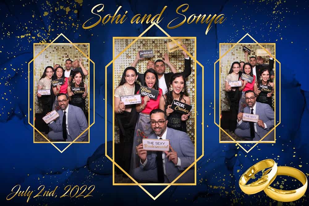Group posing at an event with gold and blue decorations, holding signs reading "Sohi and Sonya" and "July 2nd, 2022" with two gold rings illustrated.
